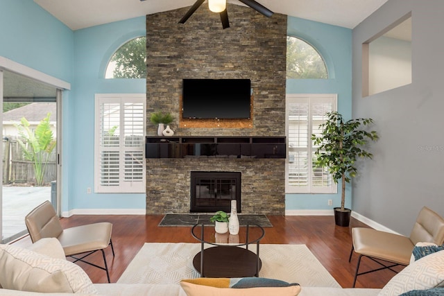 living area featuring high vaulted ceiling, a fireplace, baseboards, and wood finished floors