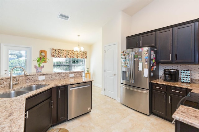kitchen with visible vents, appliances with stainless steel finishes, hanging light fixtures, light stone countertops, and a sink