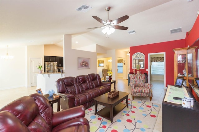 living room with vaulted ceiling, ceiling fan with notable chandelier, and visible vents