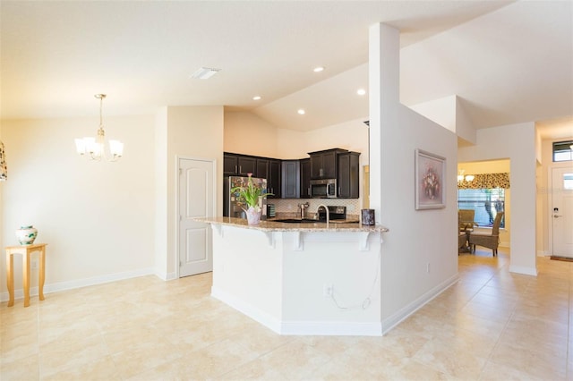 kitchen with lofted ceiling, light stone counters, a breakfast bar area, a peninsula, and appliances with stainless steel finishes