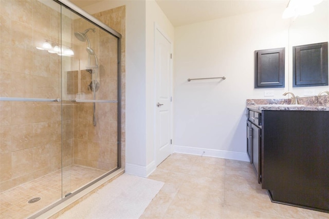 bathroom featuring a stall shower, tile patterned flooring, baseboards, and vanity
