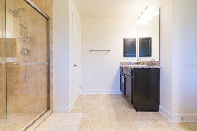 bathroom with a tile shower, vanity, and baseboards