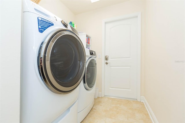 laundry room featuring laundry area, washing machine and dryer, light tile patterned floors, and baseboards