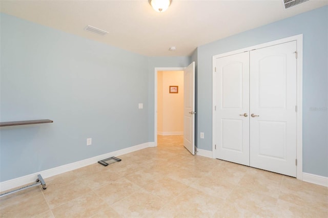 unfurnished bedroom with baseboards, visible vents, and a closet