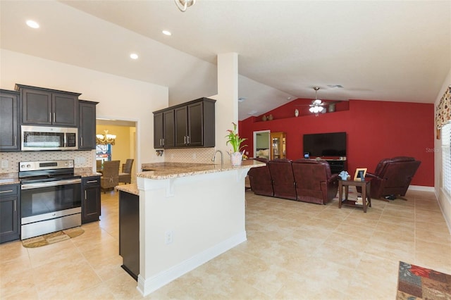 kitchen featuring lofted ceiling, light stone counters, ceiling fan with notable chandelier, stainless steel appliances, and open floor plan
