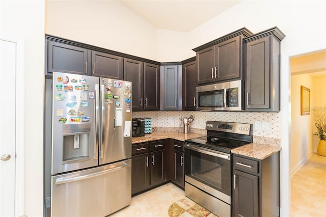 kitchen with light tile patterned floors, light stone counters, appliances with stainless steel finishes, dark brown cabinets, and backsplash