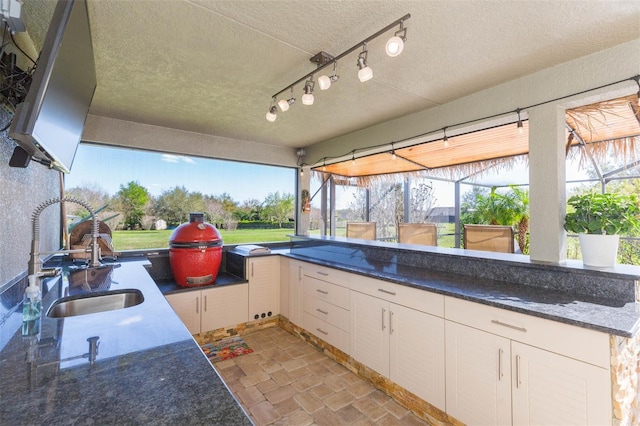 view of patio with a lanai, exterior kitchen, a sink, and outdoor wet bar