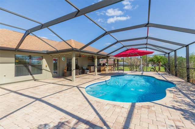 outdoor pool featuring glass enclosure, a patio, and ceiling fan