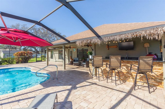 outdoor pool with a ceiling fan, a lanai, a patio area, and outdoor dry bar