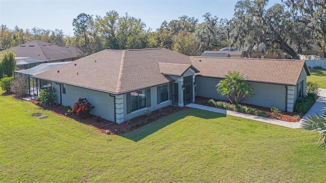 ranch-style house featuring a shingled roof, a front yard, and stucco siding