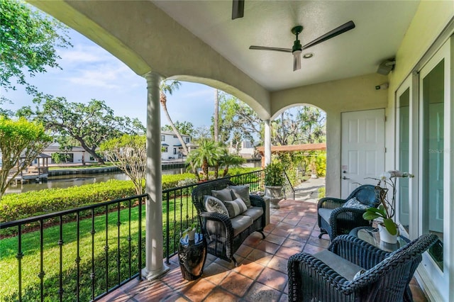 view of patio with a water view, an outdoor living space, and a ceiling fan
