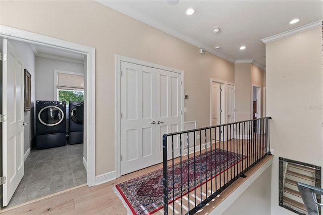 corridor featuring ornamental molding, light wood-style flooring, an upstairs landing, and separate washer and dryer