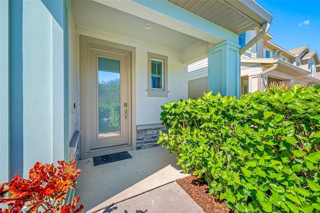 property entrance featuring stucco siding and stone siding