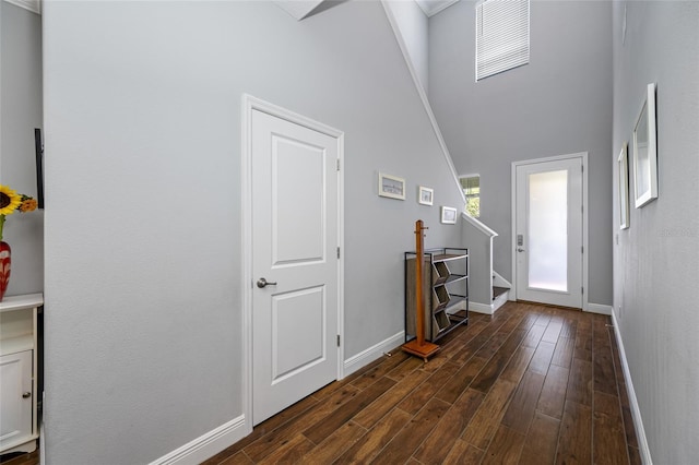 entryway with a high ceiling, stairs, dark wood-type flooring, and baseboards