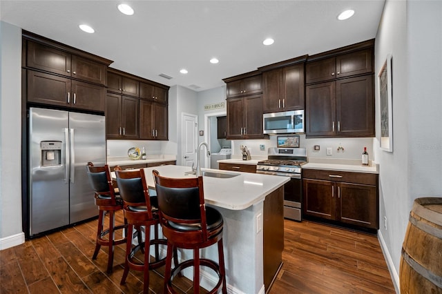 kitchen featuring dark wood-style floors, a sink, light countertops, dark brown cabinetry, and appliances with stainless steel finishes