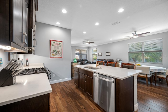 kitchen with a sink, open floor plan, stainless steel appliances, dark brown cabinets, and dark wood-style flooring