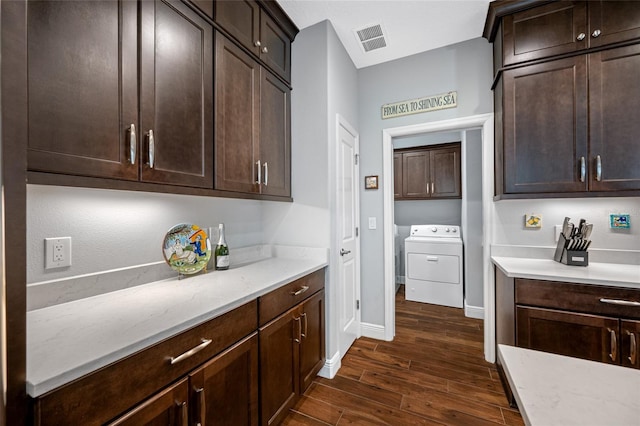 kitchen with dark wood finished floors, washer / dryer, visible vents, and dark brown cabinetry