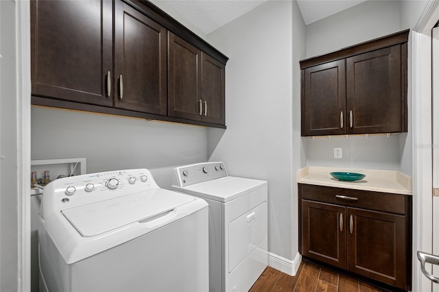 laundry area featuring washer and dryer, baseboards, cabinet space, and dark wood finished floors