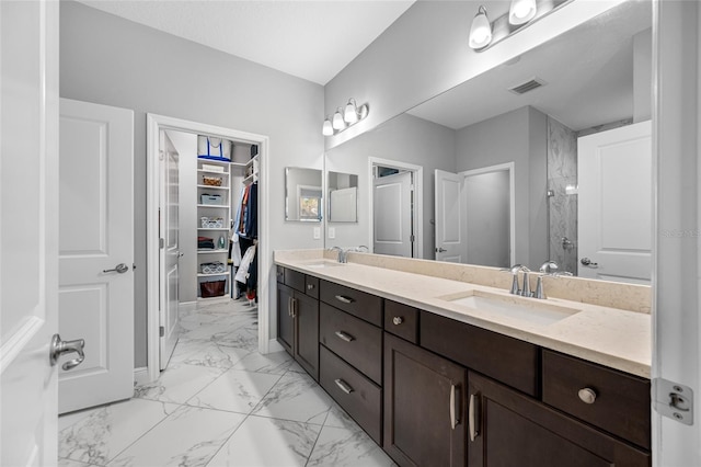 full bathroom with a sink, marble finish floor, double vanity, and a walk in shower