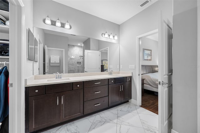 ensuite bathroom featuring a tile shower, visible vents, marble finish floor, and a sink