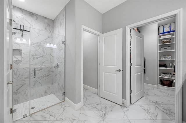 bathroom featuring baseboards, marble finish floor, and a marble finish shower