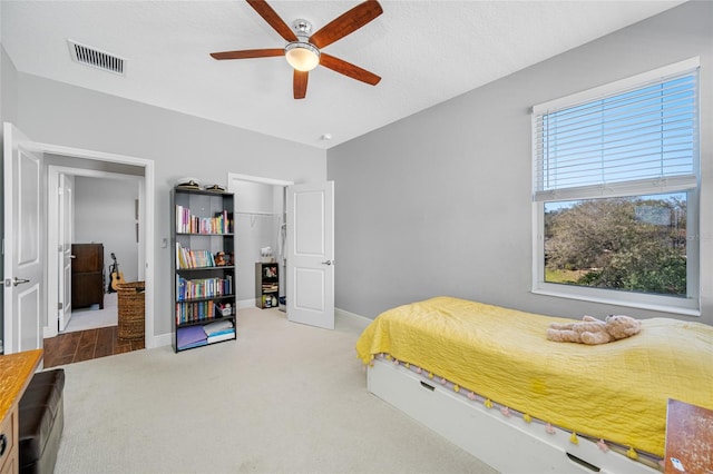 carpeted bedroom featuring a ceiling fan, baseboards, visible vents, a closet, and a textured ceiling