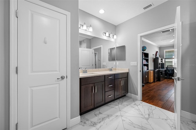 full bathroom featuring double vanity, marble finish floor, baseboards, and a sink