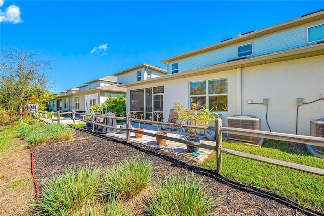 rear view of property with a sunroom, central AC unit, and fence