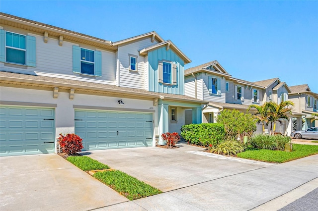 townhome / multi-family property with a garage, a residential view, board and batten siding, and concrete driveway