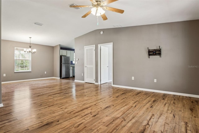 unfurnished living room with light wood-type flooring, baseboards, vaulted ceiling, and ceiling fan with notable chandelier