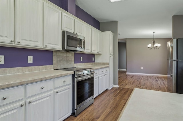 kitchen featuring dark wood finished floors, white cabinets, stainless steel appliances, and light countertops