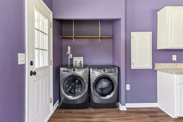 clothes washing area featuring dark wood finished floors, washing machine and dryer, cabinet space, and baseboards