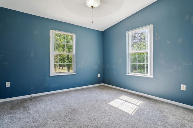 empty room with plenty of natural light, a ceiling fan, baseboards, and carpet floors