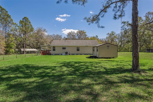 back of property with an outbuilding, central AC unit, and a yard