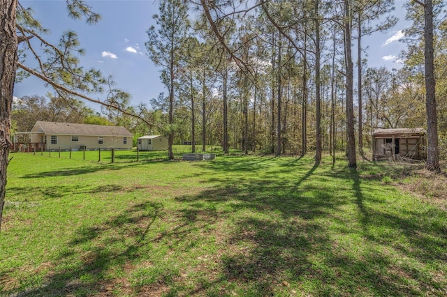 view of yard featuring a storage shed, an outdoor structure, and fence