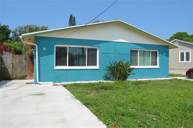 view of property exterior with brick siding, a yard, and fence