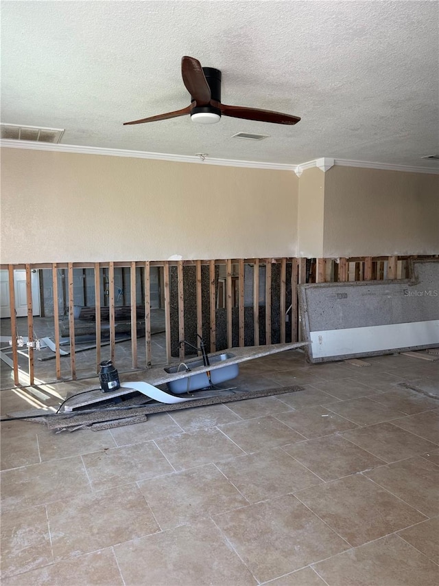 empty room featuring a textured ceiling, a ceiling fan, visible vents, and crown molding