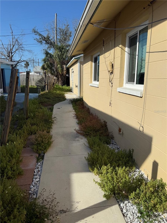 view of side of property with concrete block siding and fence