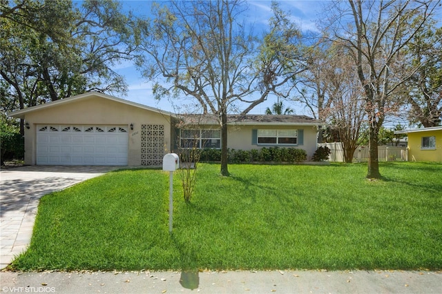 ranch-style home featuring a garage, concrete driveway, fence, a front lawn, and stucco siding