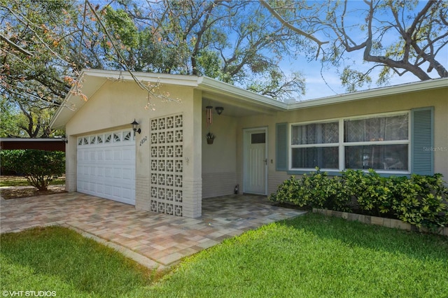 ranch-style home featuring brick siding, a front lawn, an attached garage, and stucco siding