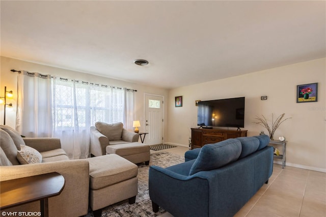 living area featuring light tile patterned floors, visible vents, and baseboards