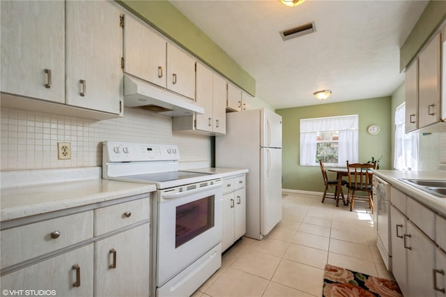 kitchen featuring white appliances, decorative backsplash, light countertops, under cabinet range hood, and light tile patterned flooring