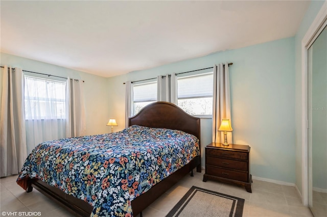 tiled bedroom featuring multiple windows, a closet, and baseboards