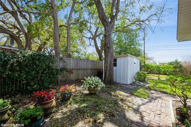 view of yard featuring a storage shed, a fenced backyard, and an outdoor structure