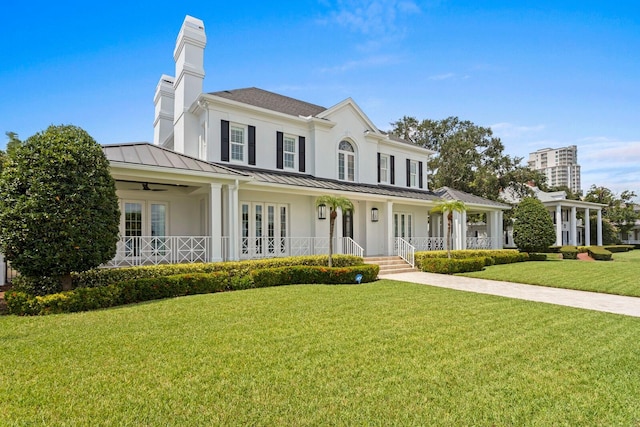 view of front of property featuring a standing seam roof, metal roof, a porch, and a front yard