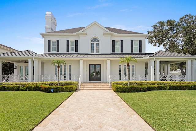 view of front of house with a standing seam roof, covered porch, and a front yard