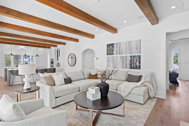 living room with a wealth of natural light, arched walkways, light wood finished floors, and recessed lighting