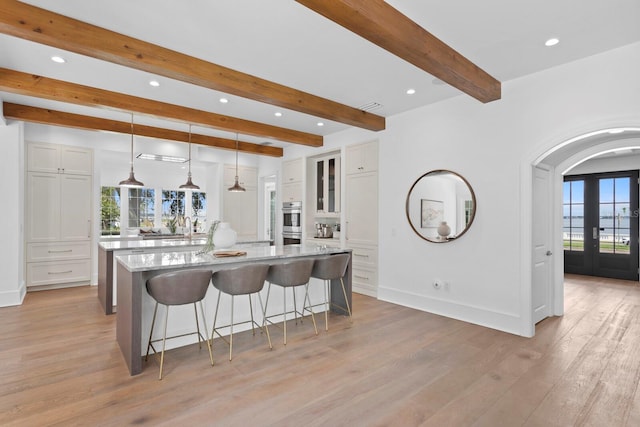 kitchen with a breakfast bar, french doors, a spacious island, white cabinets, and plenty of natural light