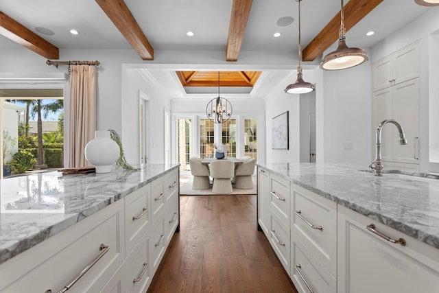 kitchen featuring white cabinets, dark wood-style floors, beamed ceiling, crown molding, and a sink