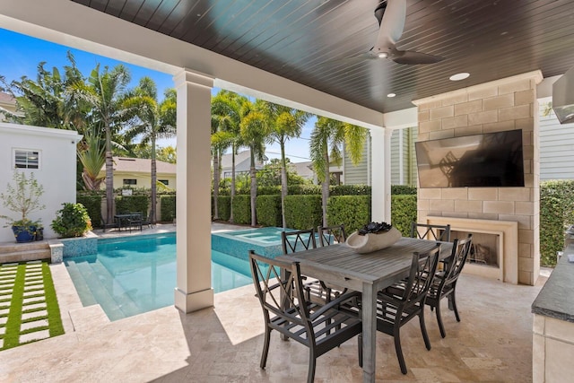 view of pool featuring a large fireplace, a patio, ceiling fan, fence, and outdoor dining space